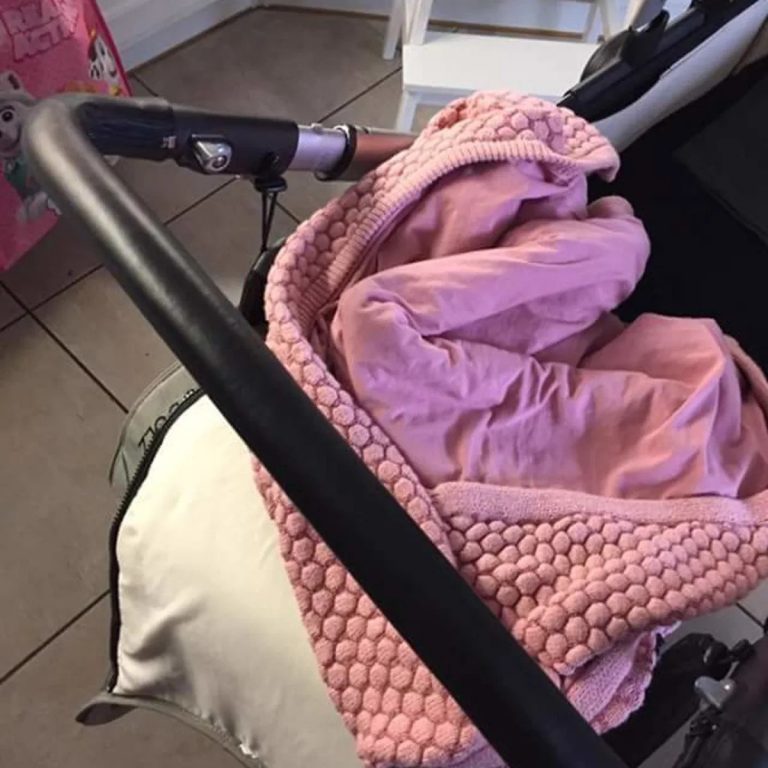Customer photo: black leather handlebar cover on a pram with a pink blanket